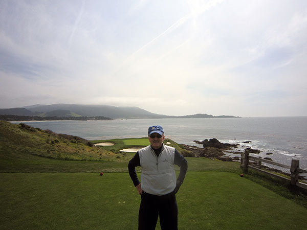 Constantine Balanis stands on the golf course that is overlooking a body of water.