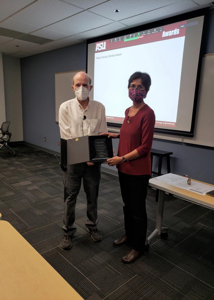 Stephen Phillips and Chaitali Chakrabata pose in a classroom holding the Joseph Palais Distinguished Faculty Award