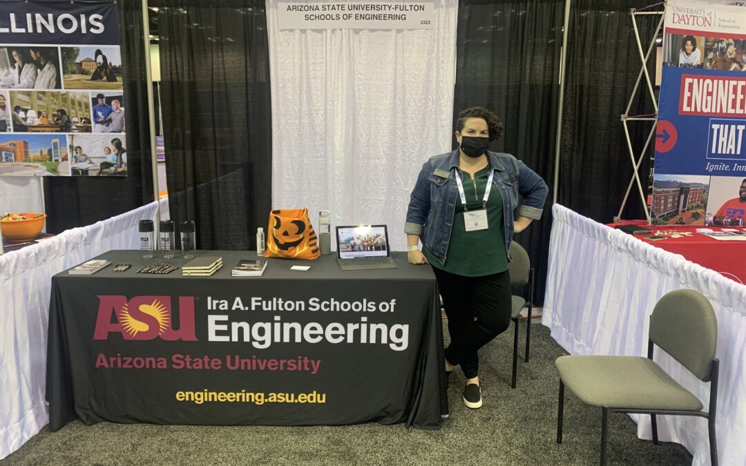 Lynn pratte stands next to her recruiting table. The table is draped in a Ira A. Fulton School of Engineering cloth.