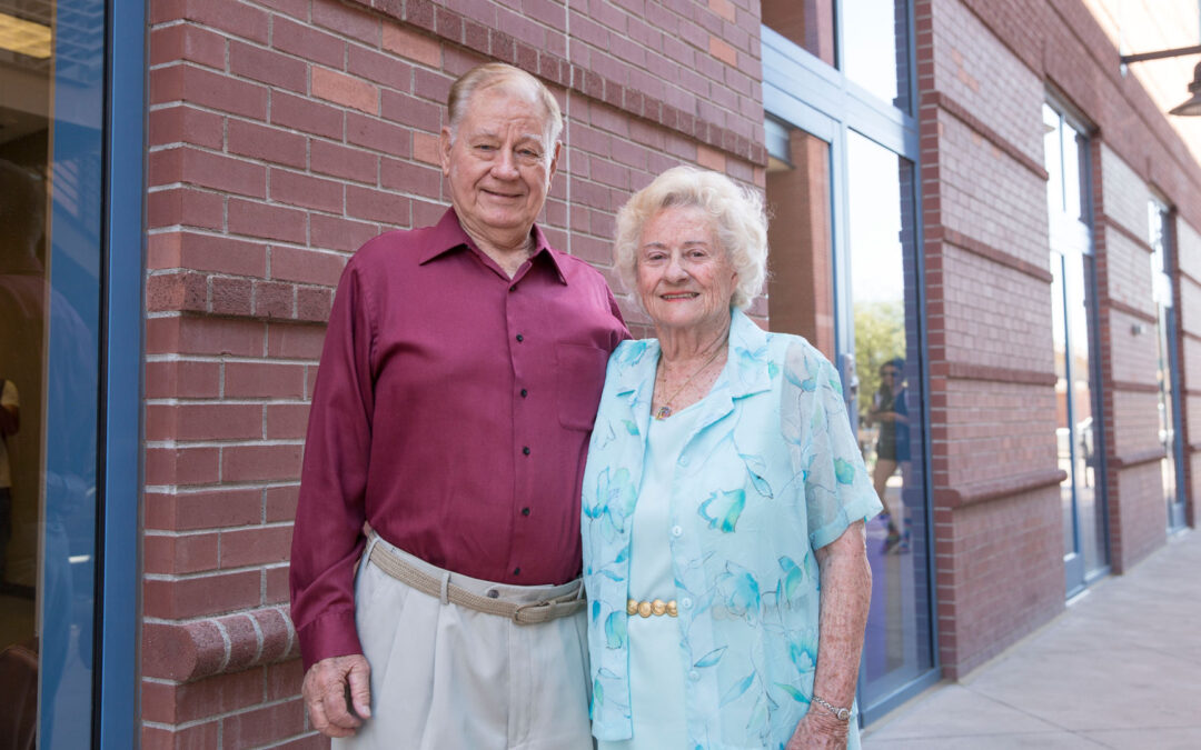 Scholarship donors Jim Schmidlin and his late wife, Marilyn Schmidlin, stand in front of a building.