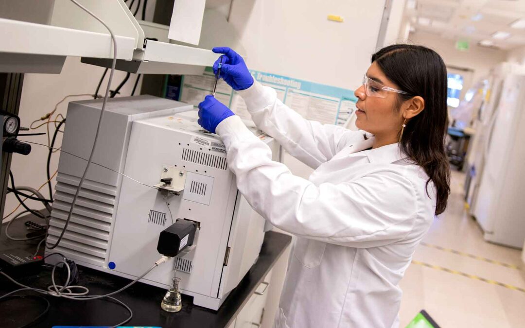 Aide Robles in a white lab coat with research equipment, studying bioremediation