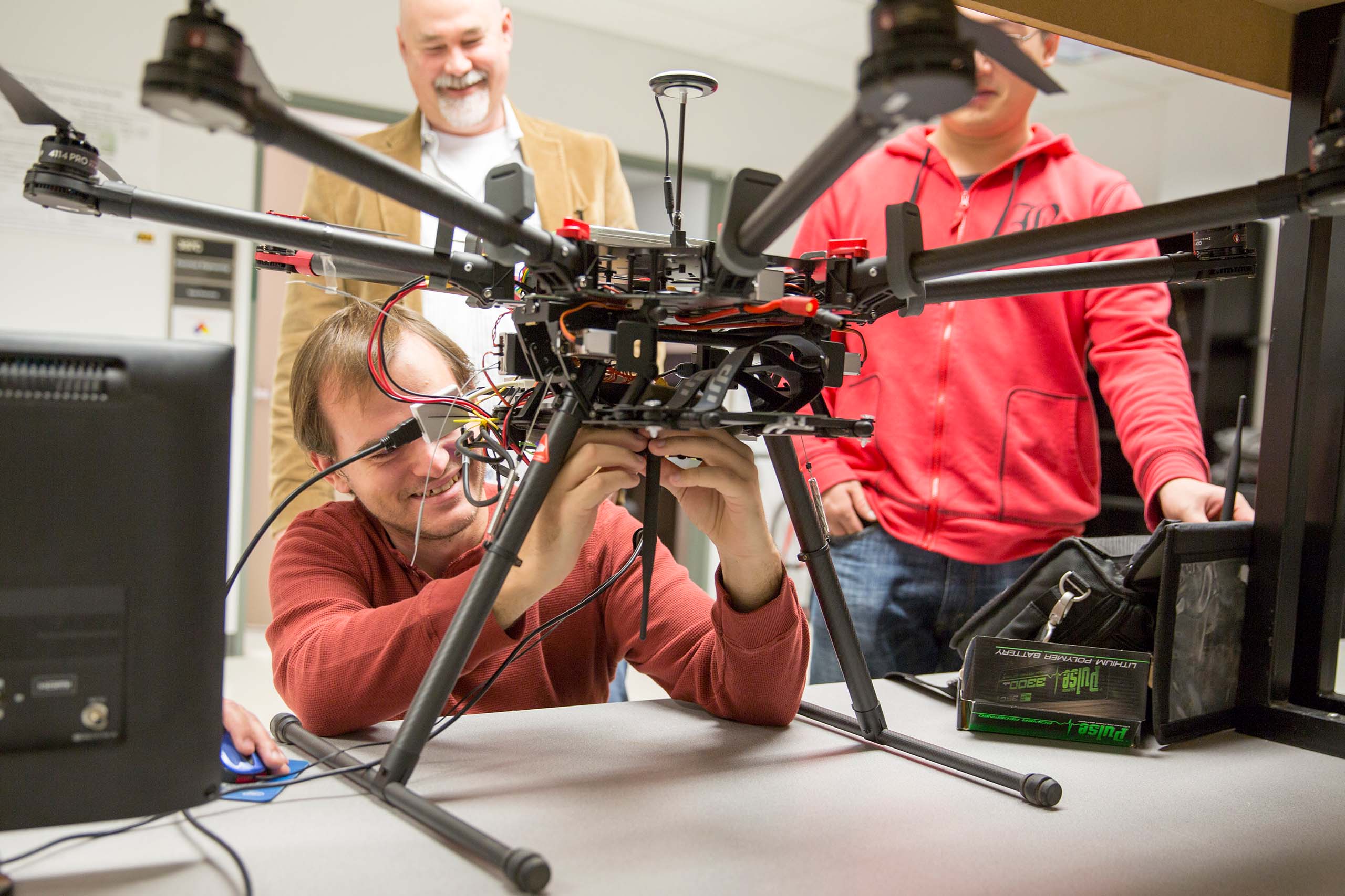 Students and faculty conduct work on a drone in a lab
