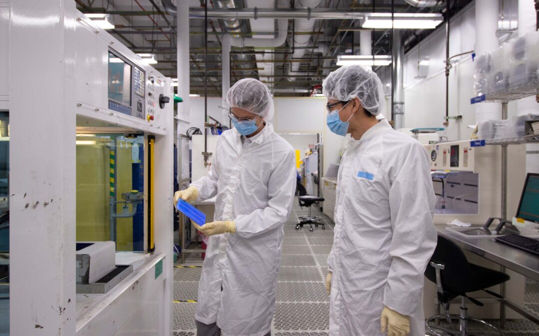 Researchers examine a solar cell in ASU's MacroTechnology Works facility.