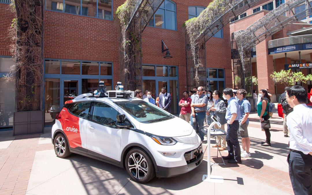 A crowd gathers around an electric autonomous vehicle at an EVSTS event on the ASU Tempe campus