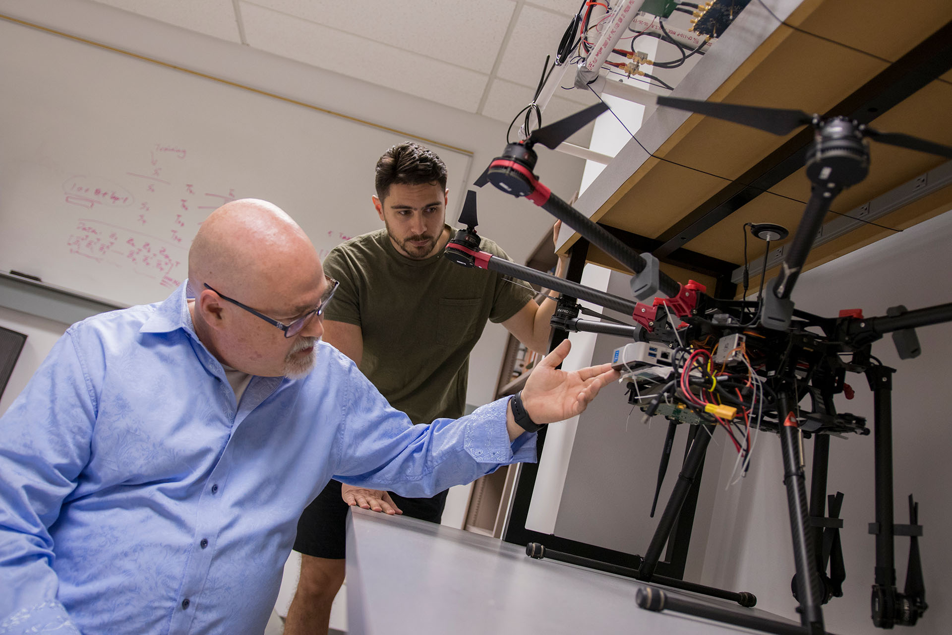 Two people inspect a drone in a lab