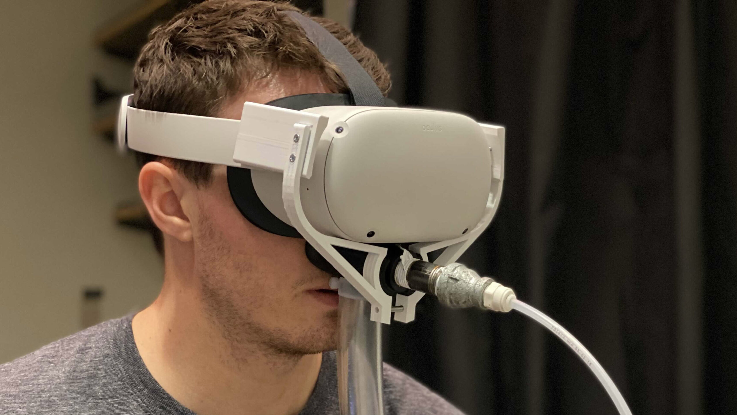 A man wears a VR headset with wires attached to the headset