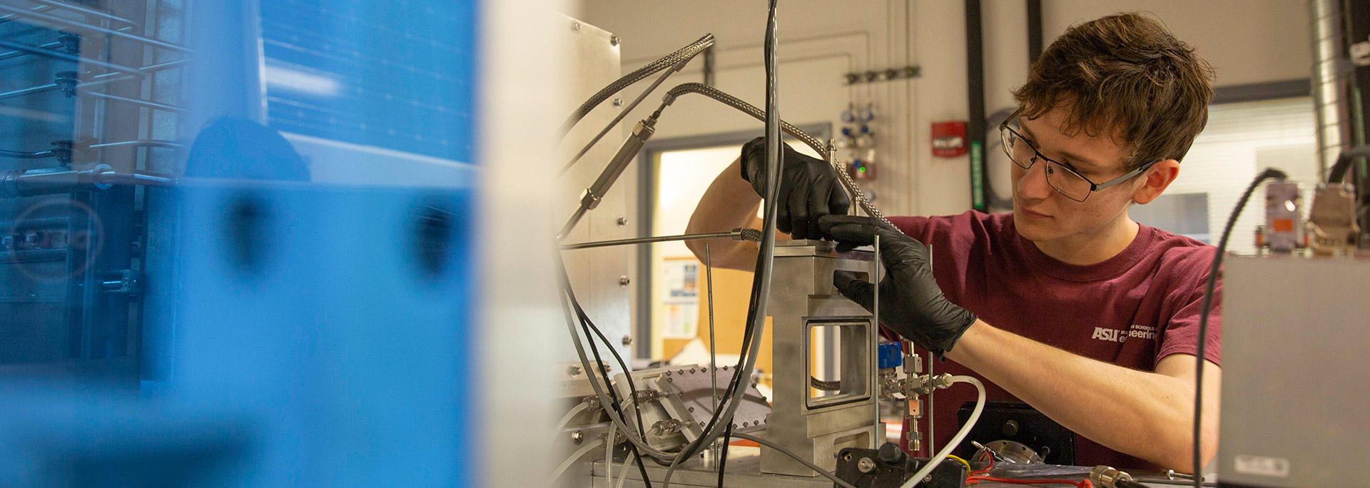 Male student fixing equipment in a lab.